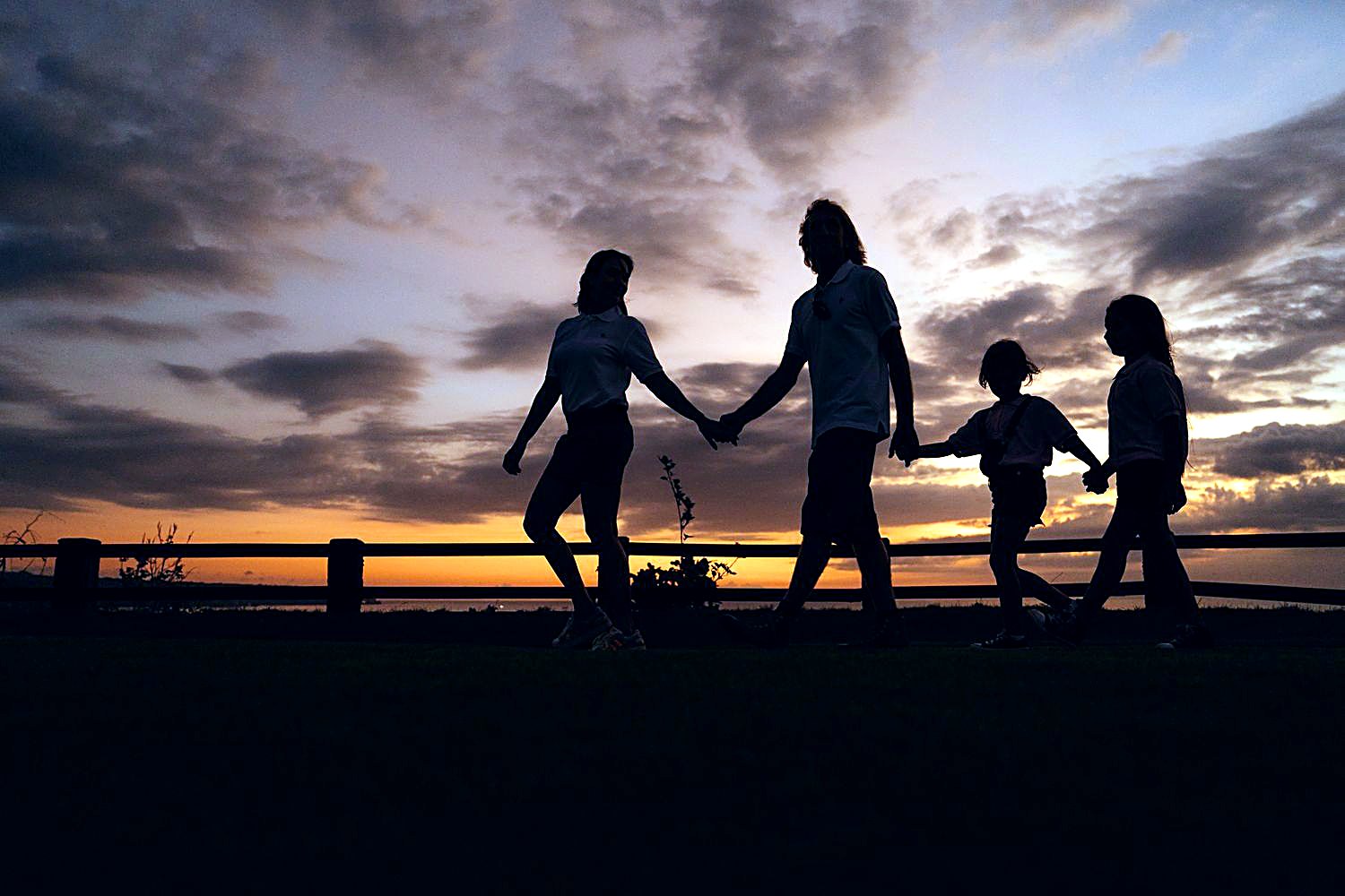 Familie geht im Sonnenuntergang Hand in Hand